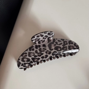 Macro shot of leopard print hair claw clip in black and gray glossy acetate finish