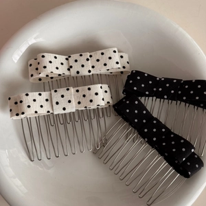 Polka dot bow hair combs in black and white styles displayed on a white ceramic plate