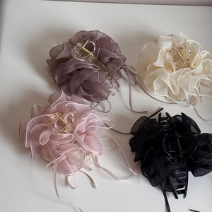 Vue détaillée de quatre grandes pinces à cheveux en organza noir, beige, violet et rose
