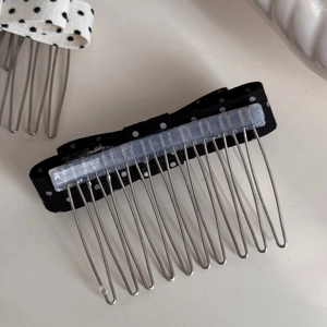 Detail of polka dot bow hair combs with silver metal teeth in black and white retro style