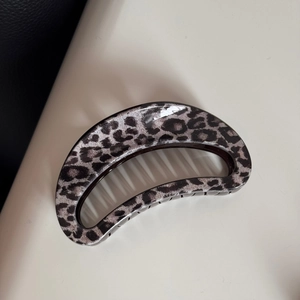 Detailed macro view of moon-shaped hair claw clip with grey leopard print and glossy finish