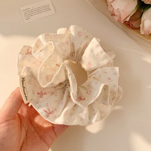 Close-up of handmade floral scrunchie with pink blossoms and handmade textile label