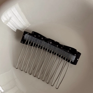 Detail view of a black and white polka dot bow hair comb with durable metal teeth