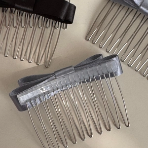 Dettaglio dei pettini per capelli con fiocco in raso nero e grigio e denti in metallo