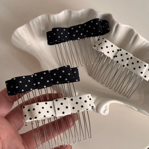 Detailed view of polka dot bow hair combs in black and white fabric with silver metal teeth