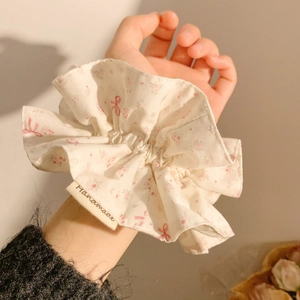 Detail of floral scrunchie with pink bow patterns and handmade tag on wrist