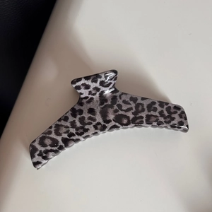 Macro detail of large black and grey leopard print hair claw clip with glossy finish
