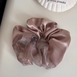Detail van bruine satijnen organza scrunchie met glittergaas en elegante textuur