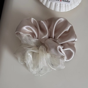 Detailweergave van champagne satijnen en witte organza patchwork haar elastiek