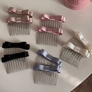 Dettaglio di pettini per capelli con fiocco in raso nei colori champagne e rosa