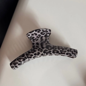 Detailed top view of a large dark grey leopard print hair claw clip with a glossy finish