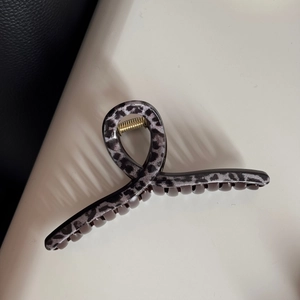 Macro detail of leopard print hair claw clip with durable gold metal spring mechanism