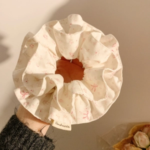 Close-up of floral print scrunchie with pink bows and handmade woven label detail