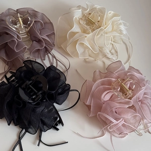 Détail de quatre pinces à cheveux en mousseline plissée grise, crème, noire et rose