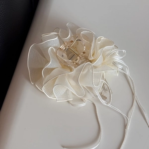 Détail d'une grande pince à cheveux en gaze plissée crème avec clip en résine