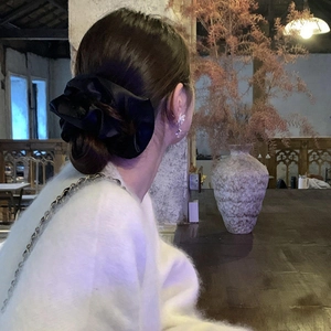 Detailansicht eines eleganten schwarzen Satin-Haargummis, gestylt an einem Damen-Haarknoten