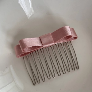 Dettaglio del pettine per capelli con fiocco in raso rosa e denti in metallo argento