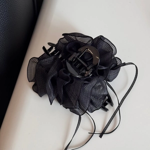 Détail de la pince à cheveux fleurie en tulle noir avec paillettes argentées et rubans