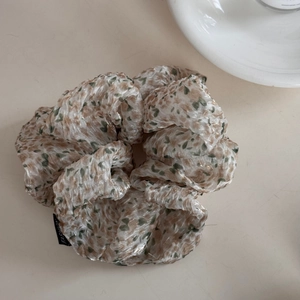 Detail of floral scrunchie with semi-transparent fabric and black fashion label