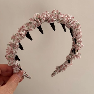 Detail showing the floral fabric texture and black toothed inner comb of the hairband