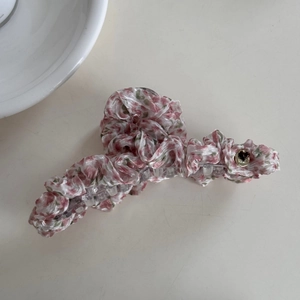 Detail of floral fabric hair claw clip with pink ruffles and golden heart ornament