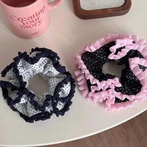 Detail of two chiffon polka dot scrunchies with pleated lace ruffles in black and white