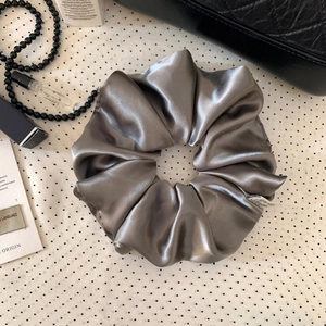 Nahaufnahme von elegantem silbergrauem Satin-Haargummi mit seidigem Glanz und Textur
