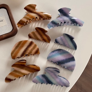 Detail view of colorful twill claw clips set in brown and blue gradient acetate finish