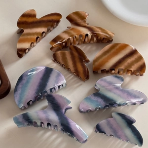 Macro detail of various vintage twill hair claws in brown wood and blue watercolor patterns