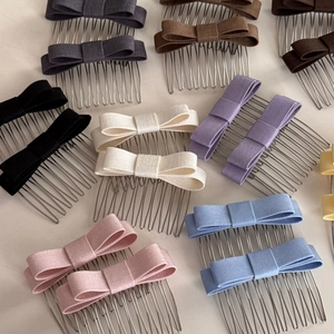 Detailed view of assorted fabric bow hair combs in black, pink, and pastel colors