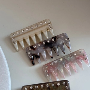 Close-up of four acetate hair comb clips with rhinestone detailing in diverse marble patterns