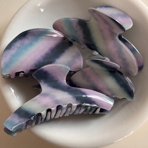 Detailed view of four colorful marble pattern hair claws in a white ceramic bowl decoration