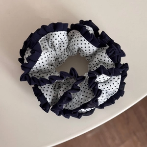 Close-up of pleated polka dot hair scrunchie with elegant blue ruffled lace edges