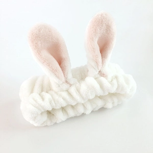Detailed close-up of soft white plush rabbit ear headband with pink inner accents