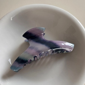 Detail of purple marble pattern acetate hair claw clip resting in white ceramic bowl