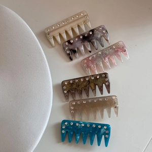 Detailed macro view of six colorful rhinestone acetate hair combs on a white background