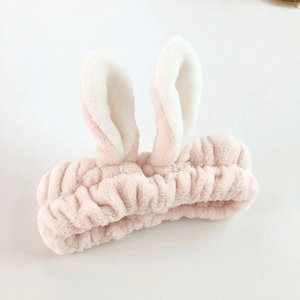 Close-up of soft plush pink and white rabbit ear headband for washing face and makeup