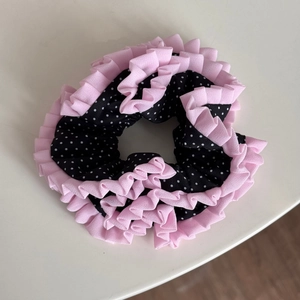 Close-up of pleated black polka dot hair scrunchie with layered pink lace trim edges