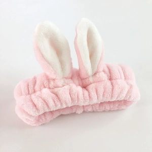 Detailed view of pink coral fleece rabbit ear headband showing soft plush fabric texture