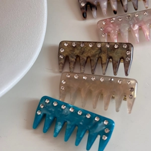 Detail view of five assorted rhinestone comb hair clips in marble and solid colors