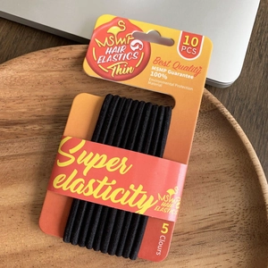Detail of high-elasticity black hair ties in a wooden tray with minimal office aesthetic