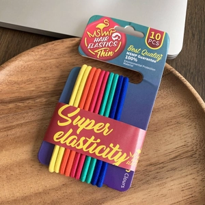 Detail showing 10-piece rainbow elastic hair ties on a blue brand card set