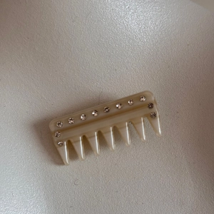 Detailed view of a cream-colored rhinestone hair comb clip with elegant resin texture