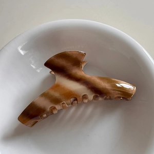 Detailed view of a brown marble acetate hair claw clip with a glossy finish for women