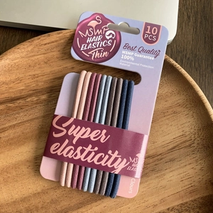 Detail of 10-piece high-elasticity hair ties in assorted muted candy colors on wood