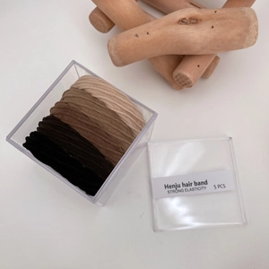 Detailed view of high elasticity hair bands in earth tones inside a clear plastic storage box