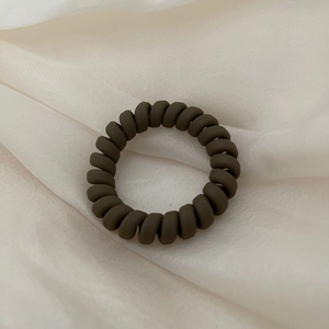 Deep olive green frosted spiral phone cord hair tie on elegant cream silk fabric