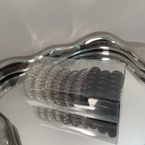Close-up of gradient spiral hair ties set in a transparent storage box on a silver tray