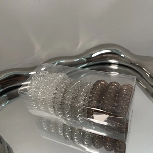 Set of 9 spiral hair ties in gradient shades within a minimalist clear storage box