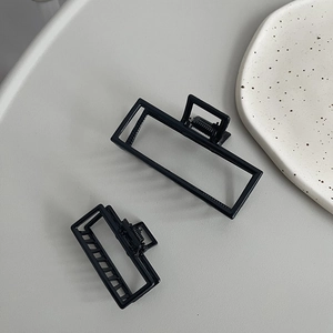 Minimalist black matte rectangular hair claws set for high ponytail styling on grey surface